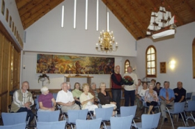 Menighedsr�dets formand Ebbe Juul Hansen modtog p� alles vegne buketten af Solkystens Henrik S. Andersen. Mange af hj�lperne var vidner til begivenheden. Det var en ganske almindelig onsdag eftermiddag, men der er altid aktivitet i kirkebygningen. Foto: N